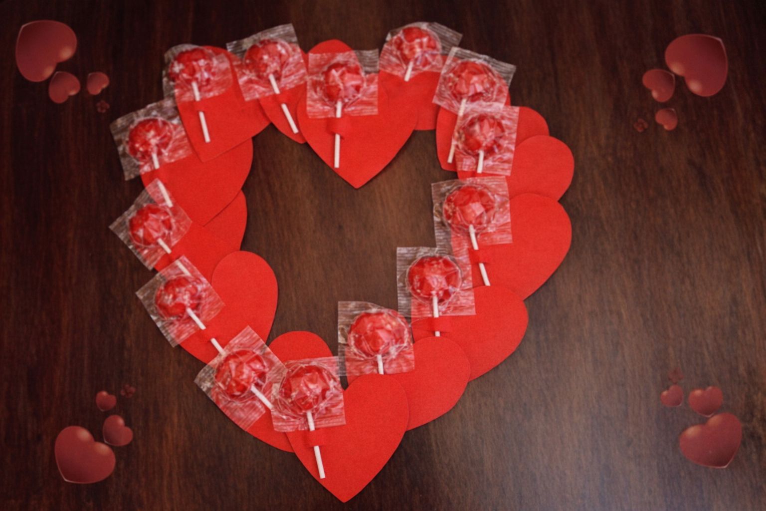 Röda pappershjärtan och klubbor bildar ett stort hjärta på träbakgrund.