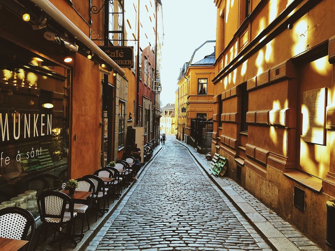Kullerstensgata i Gamla Stan i Stockholm med caféer och historiska byggnader.