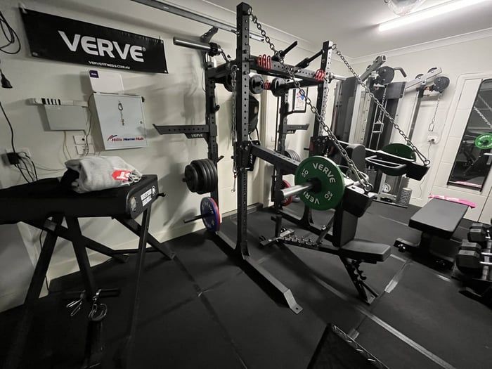 Kompakt hemmagym med powerrack, viktskivor och träningsbänk i ett garage.